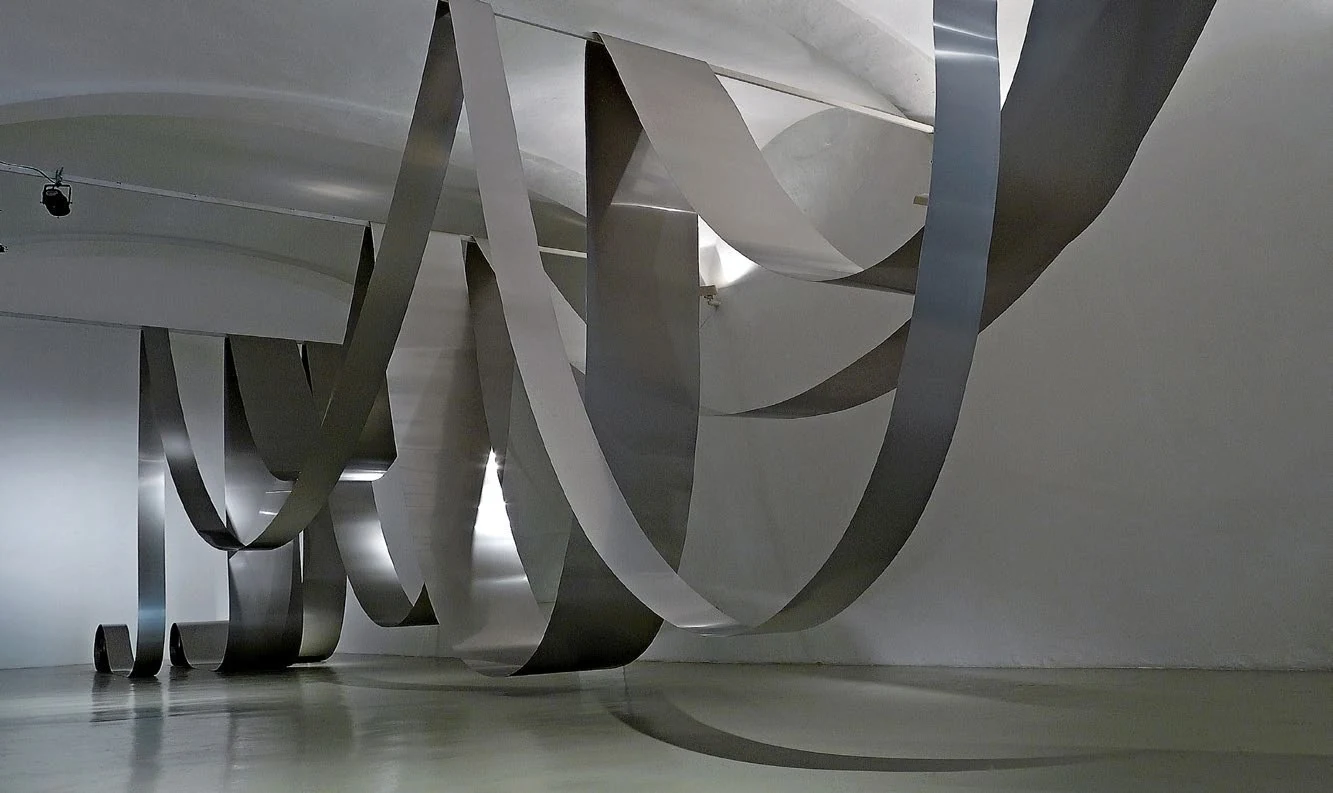 Morbida 120, monumental ribbons of stainless steel unfolding through a gallery