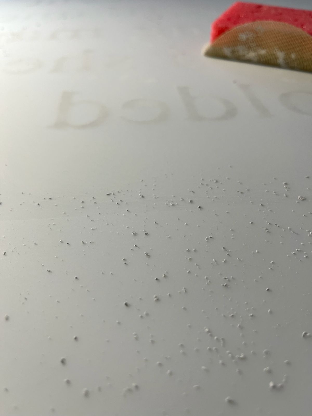 Close view of a pale abraded surface with faint lettering and material residue