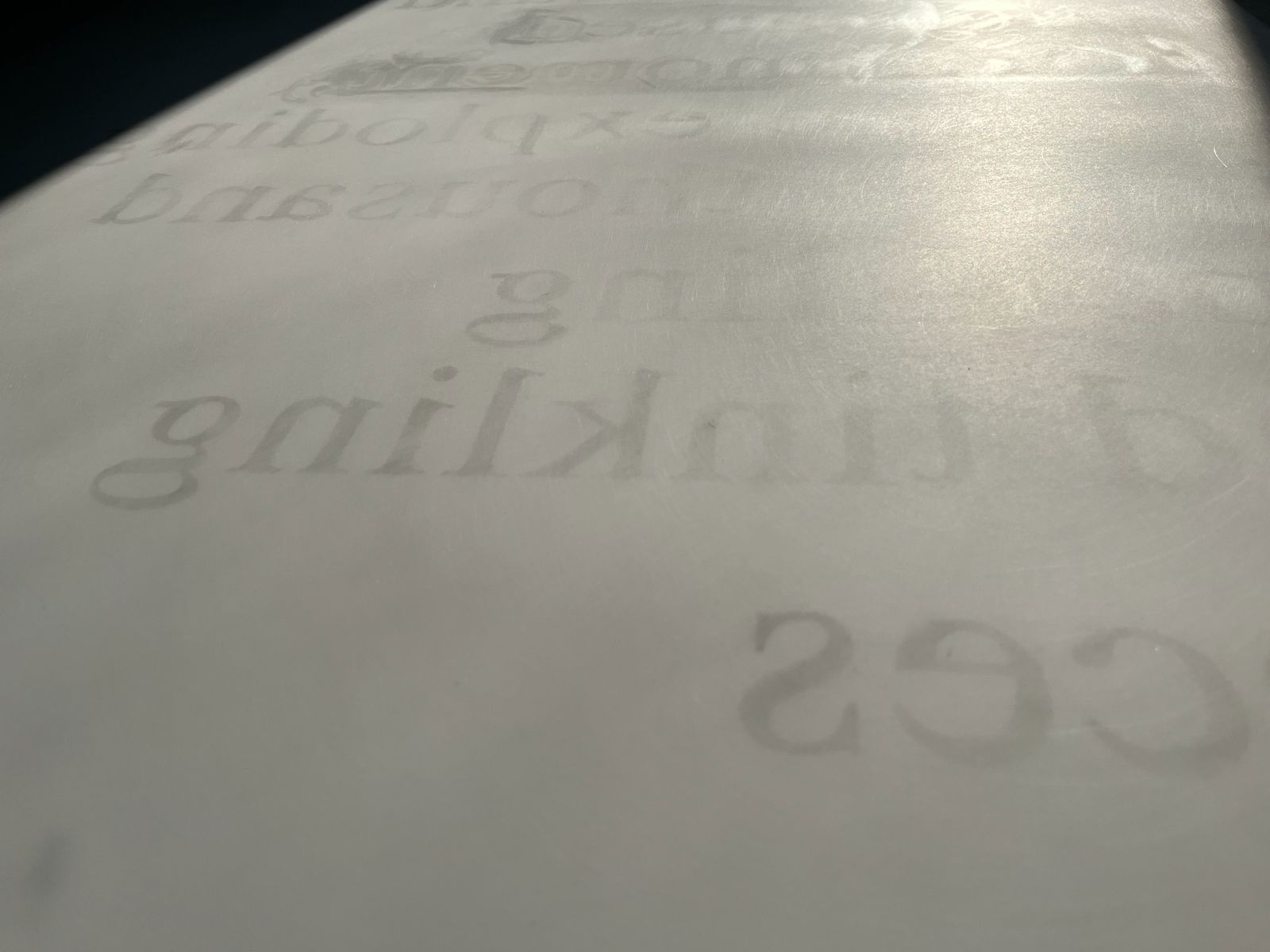 Oblique close view of faint reversed lettering on a pale surface